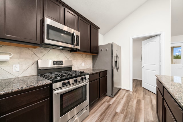 kitchen featuring vaulted ceiling, light wood-type flooring, appliances with stainless steel finishes, light stone counters, and dark brown cabinetry