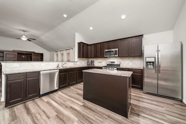 kitchen with vaulted ceiling, ceiling fan, appliances with stainless steel finishes, tasteful backsplash, and a kitchen island