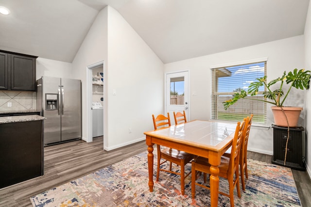 dining space with dark hardwood / wood-style floors, vaulted ceiling, and a healthy amount of sunlight