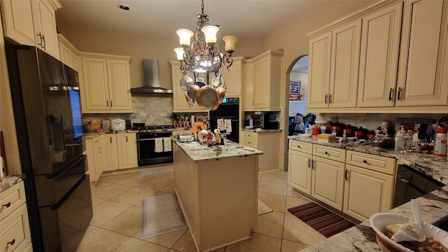 kitchen featuring a center island, light stone counters, black appliances, and wall chimney range hood