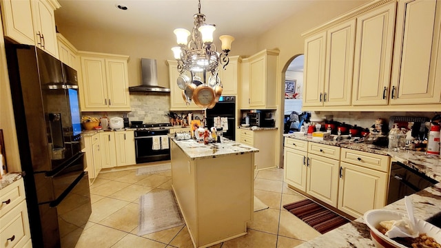 kitchen with cream cabinetry, black appliances, a center island, and wall chimney exhaust hood