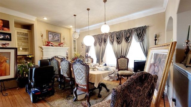 dining space with built in shelves, ornamental molding, and hardwood / wood-style floors