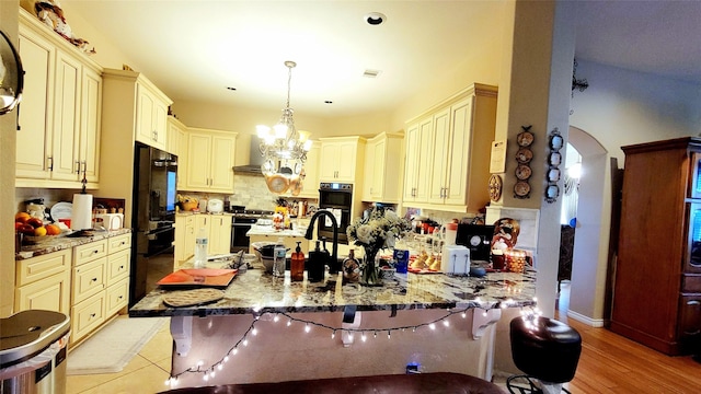 kitchen with decorative light fixtures, a chandelier, a kitchen breakfast bar, light stone counters, and kitchen peninsula