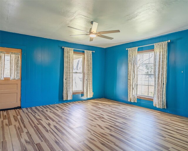 spare room featuring ceiling fan, hardwood / wood-style flooring, and a healthy amount of sunlight