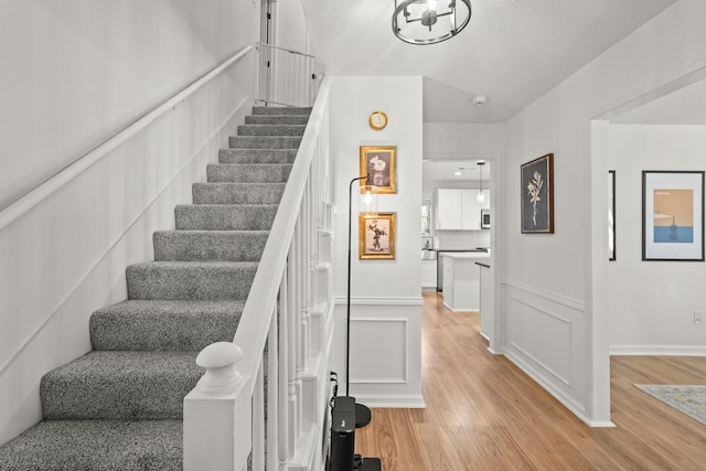 stairway with hardwood / wood-style floors and a textured ceiling