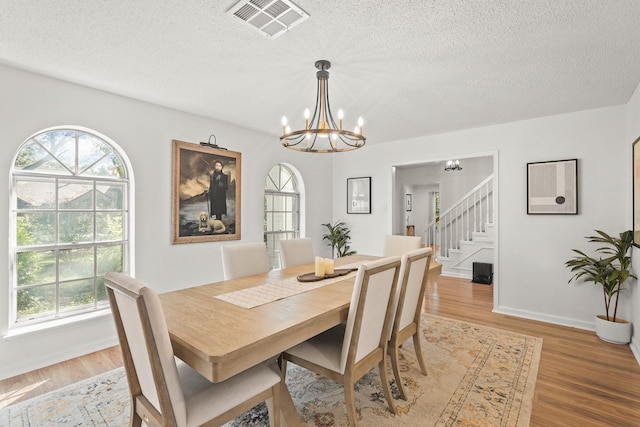 dining space featuring a notable chandelier, light wood-type flooring, and a wealth of natural light