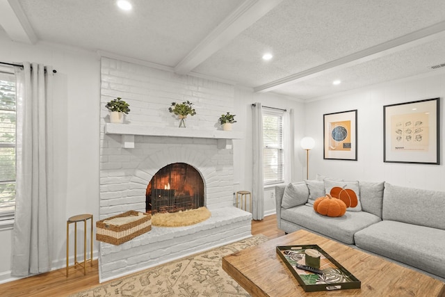 living room featuring hardwood / wood-style floors, a fireplace, beam ceiling, and a textured ceiling