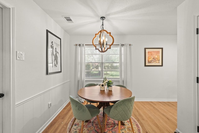 dining area with a chandelier, wood-type flooring, and a textured ceiling