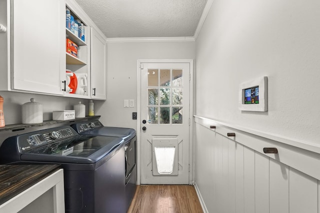 washroom featuring cabinets, hardwood / wood-style floors, a textured ceiling, washer and clothes dryer, and ornamental molding