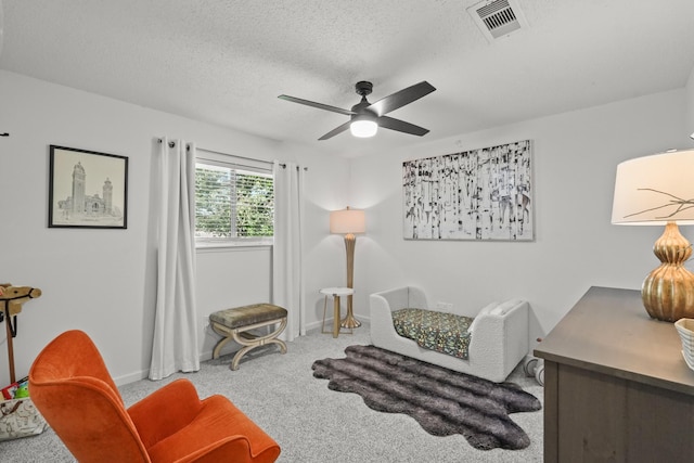 sitting room featuring carpet flooring, ceiling fan, and a textured ceiling