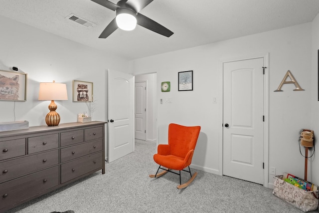 sitting room with ceiling fan, light colored carpet, and a textured ceiling