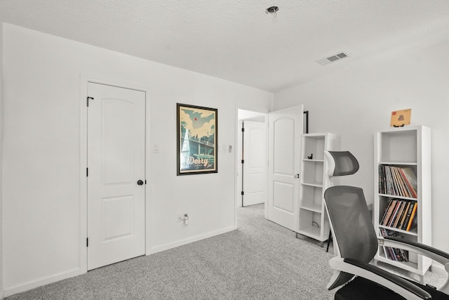 carpeted office with a textured ceiling