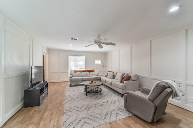 living room featuring crown molding, ceiling fan, and light hardwood / wood-style floors