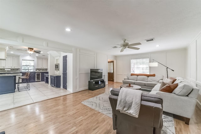 living room featuring a healthy amount of sunlight, ceiling fan, and light hardwood / wood-style flooring