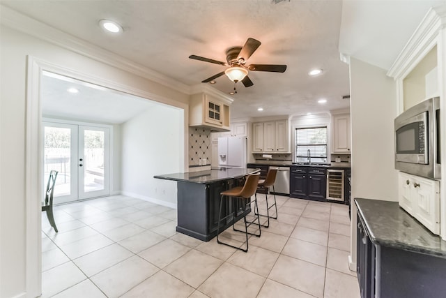 kitchen featuring french doors, wine cooler, a kitchen bar, appliances with stainless steel finishes, and decorative backsplash