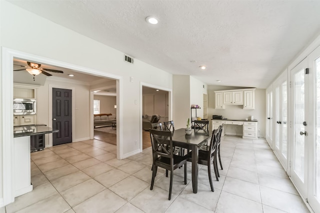 dining room with ceiling fan, vaulted ceiling, a textured ceiling, and light tile patterned floors