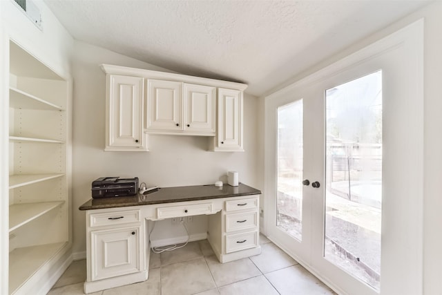 tiled home office with built in desk, french doors, a textured ceiling, and vaulted ceiling