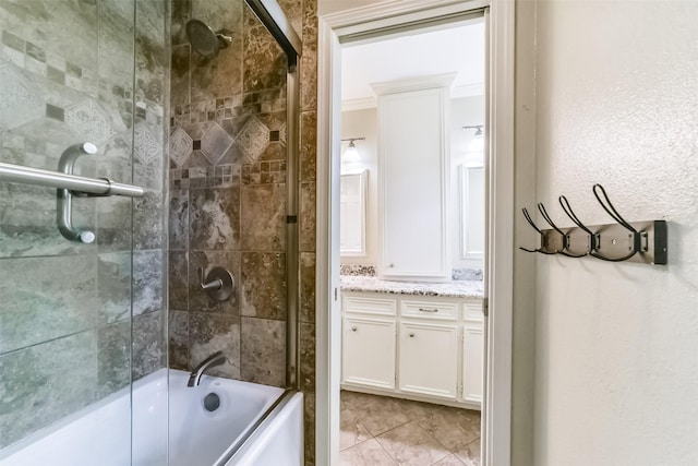 bathroom featuring tile patterned floors, ornamental molding, combined bath / shower with glass door, and vanity