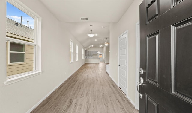 corridor with light hardwood / wood-style floors and lofted ceiling