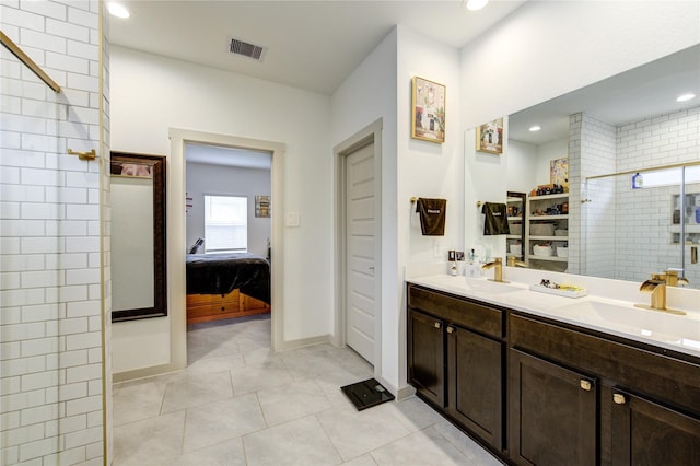 bathroom with tile patterned flooring, a tile shower, and vanity