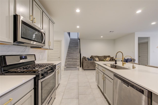 kitchen with backsplash, gray cabinetry, stainless steel appliances, sink, and light tile patterned flooring