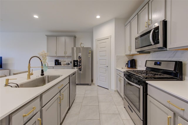 kitchen featuring gray cabinetry, backsplash, sink, light tile patterned floors, and appliances with stainless steel finishes