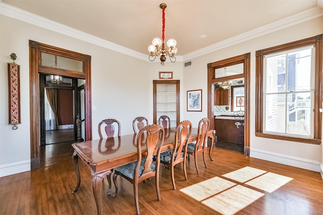 dining area with wood-type flooring, crown molding, and a chandelier