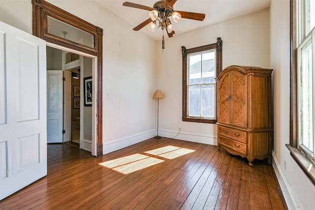 unfurnished bedroom with ceiling fan and dark wood-type flooring