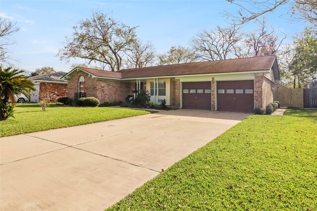 ranch-style house featuring a front yard, fence, driveway, an attached garage, and brick siding