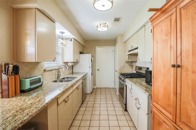 kitchen with visible vents, under cabinet range hood, appliances with stainless steel finishes, light tile patterned flooring, and a sink