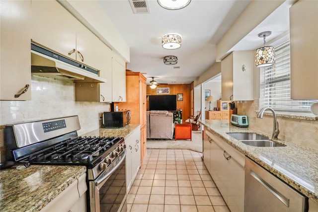 kitchen featuring light stone countertops, pendant lighting, appliances with stainless steel finishes, sink, and light tile patterned flooring