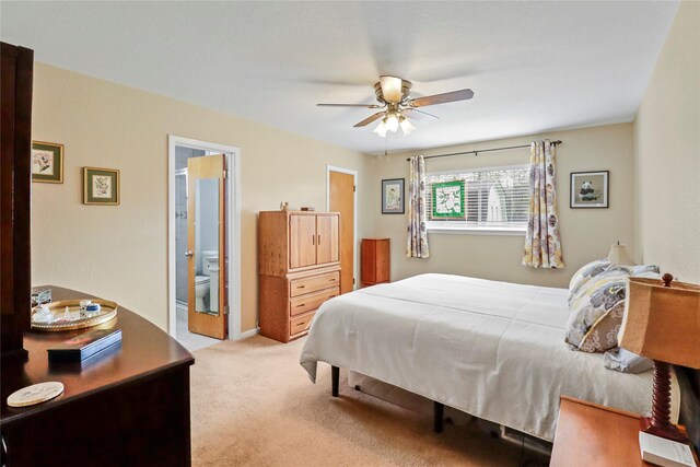 carpeted bedroom with ensuite bathroom and a ceiling fan