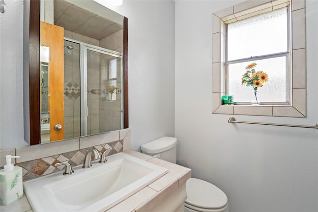 bathroom with a shower with shower door, sink, and toilet