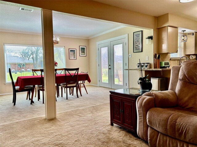 living area with visible vents, light carpet, ornamental molding, french doors, and baseboards