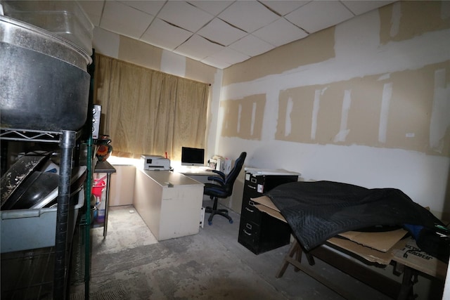 home office featuring a drop ceiling and concrete flooring