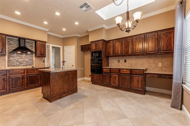 kitchen with a kitchen island, a skylight, decorative light fixtures, black appliances, and wall chimney exhaust hood