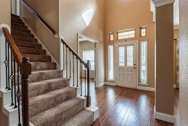 entryway with dark wood-type flooring and a towering ceiling