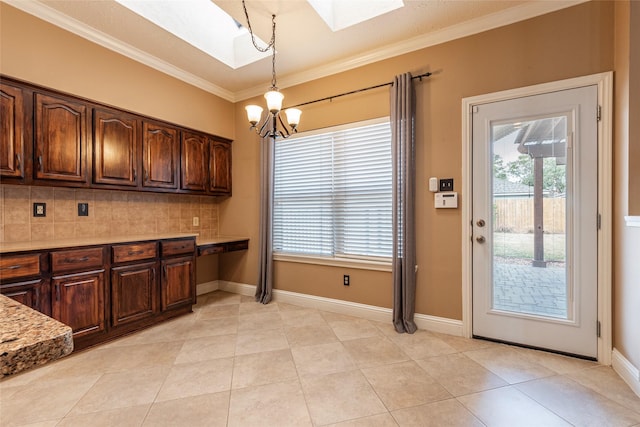 kitchen with hanging light fixtures, a skylight, dark brown cabinets, ornamental molding, and decorative backsplash