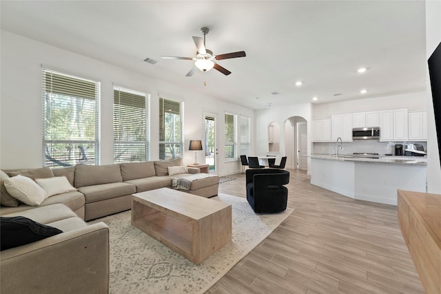 living room with light hardwood / wood-style floors, ceiling fan, and sink