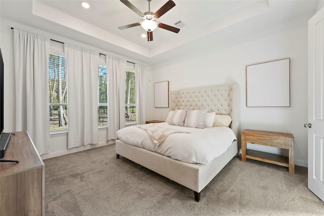 carpeted bedroom featuring a tray ceiling and ceiling fan