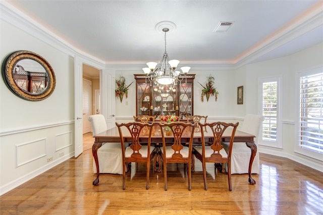 dining area featuring a chandelier, light wood-type flooring, and crown molding