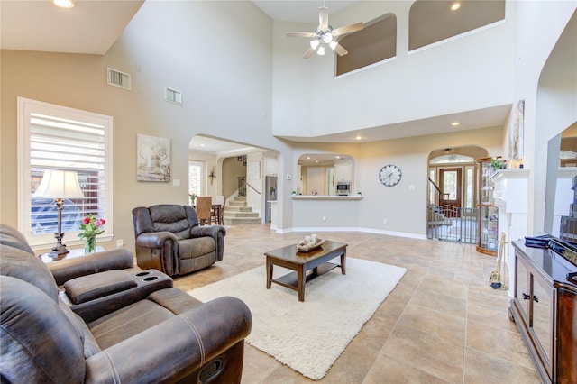 living room with ceiling fan and a towering ceiling