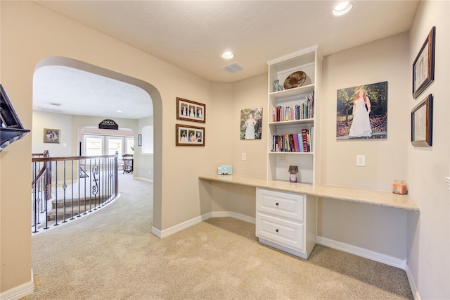 home office with light carpet, french doors, and built in desk