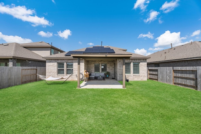 back of property with a lawn, an outdoor living space, a patio, and solar panels