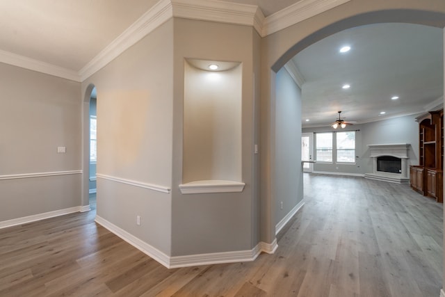 hallway with ornamental molding and light hardwood / wood-style flooring