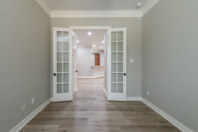 spare room featuring ornamental molding, french doors, and light hardwood / wood-style floors