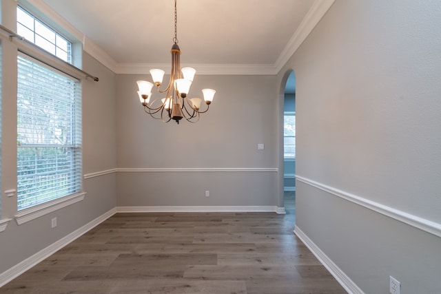 unfurnished dining area featuring ornamental molding, a notable chandelier, and dark wood-type flooring