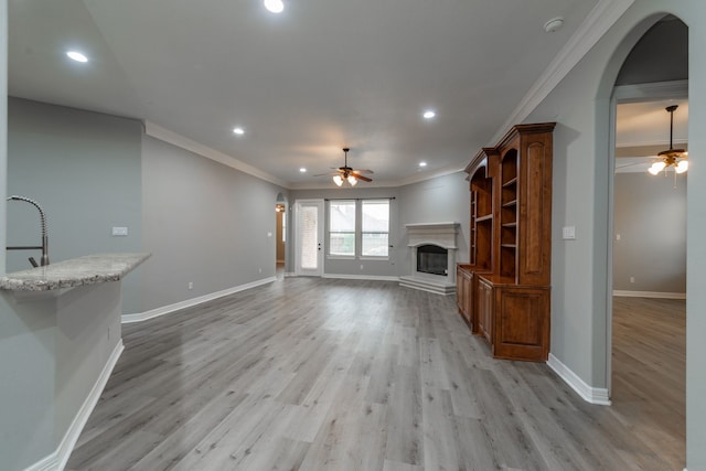 unfurnished living room featuring sink, ceiling fan, light hardwood / wood-style floors, and ornamental molding