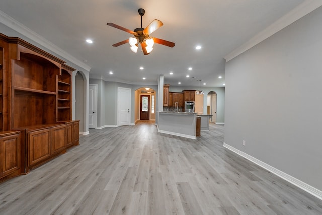 unfurnished living room featuring ornamental molding, ceiling fan, and light wood-type flooring