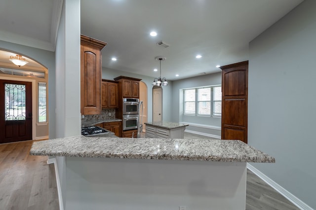 kitchen featuring appliances with stainless steel finishes, light hardwood / wood-style flooring, tasteful backsplash, and a center island